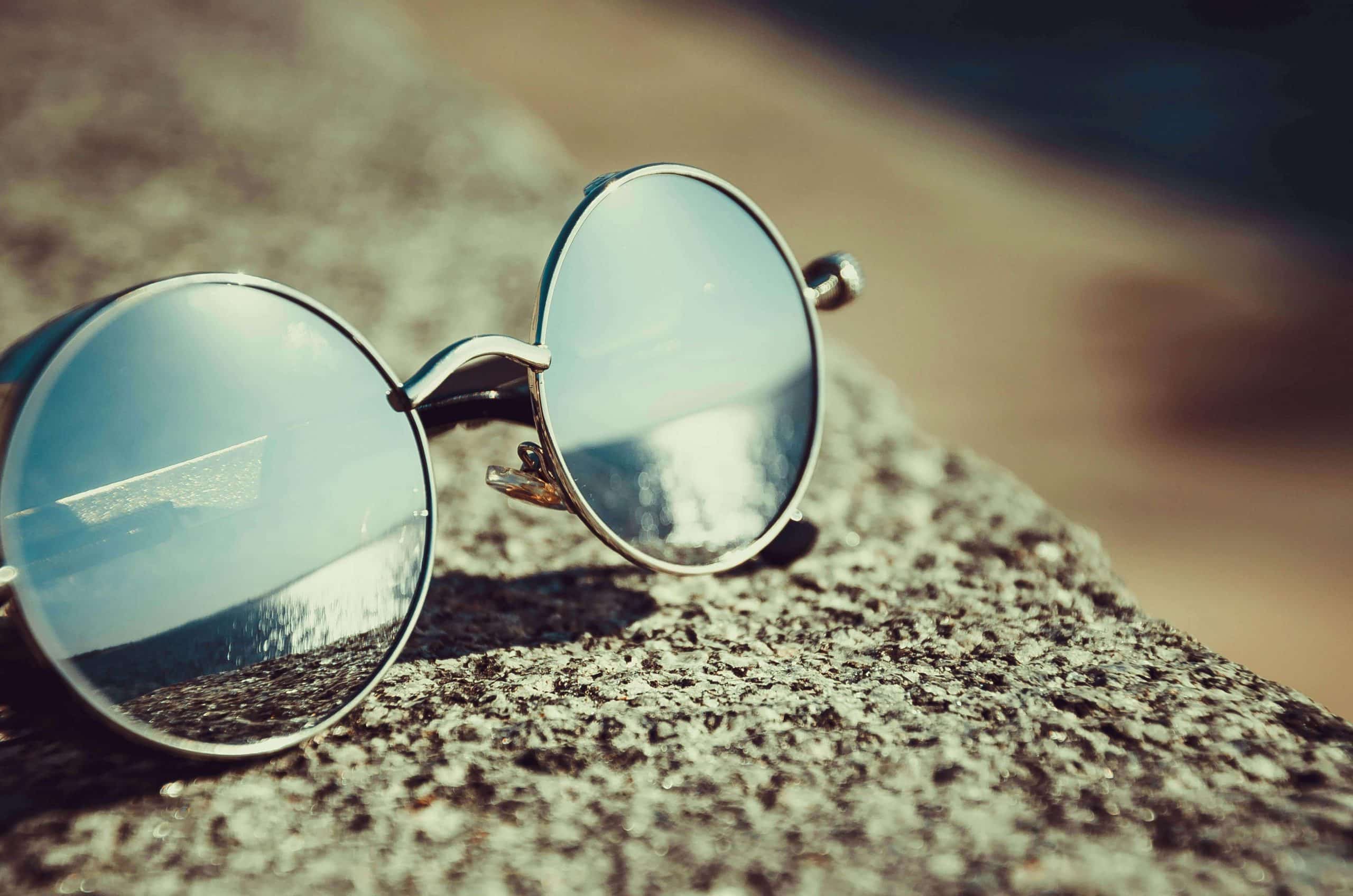 A pair of circular glasses resting on a wall.